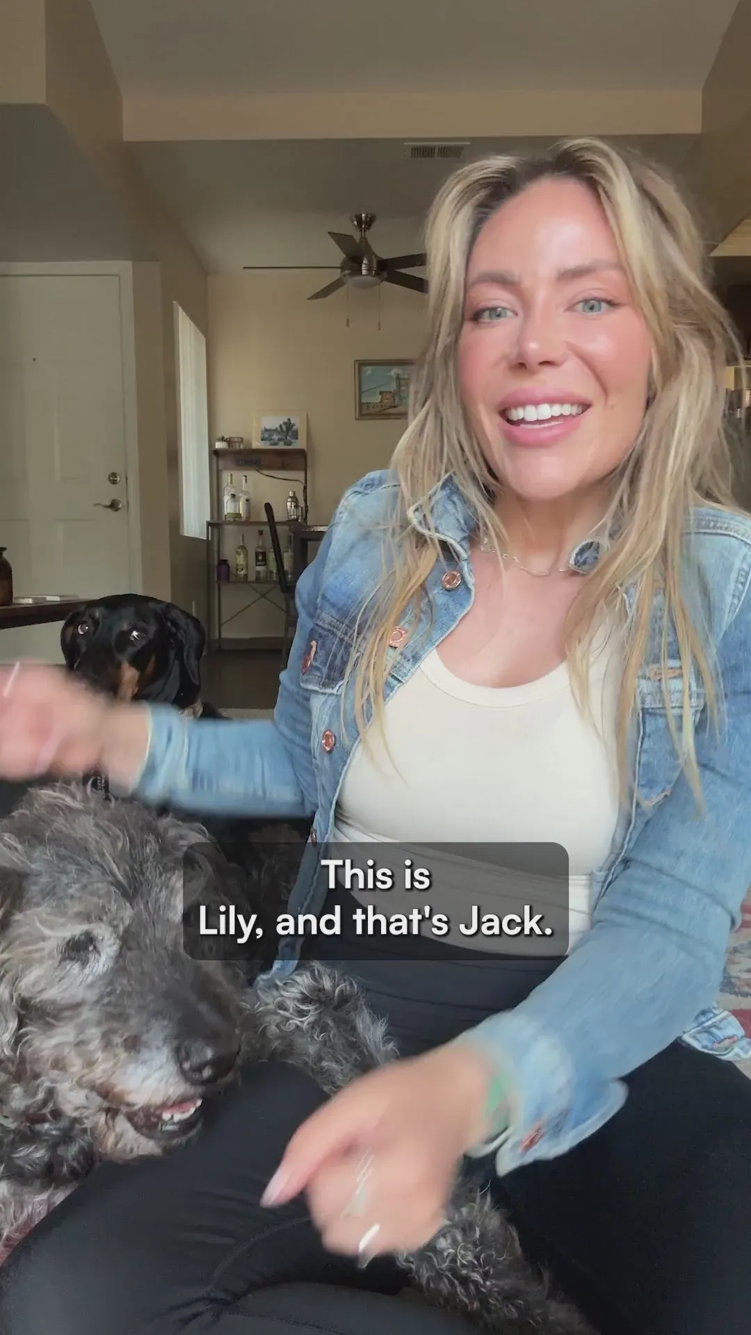 A woman in a denim jacket on her sofa introducing her two dogs, Lily and Jack