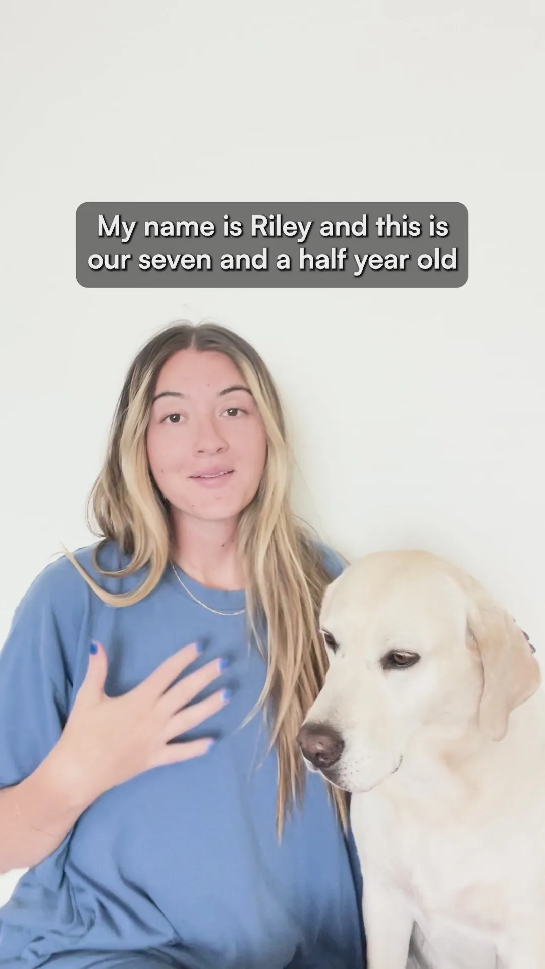 A woman named Riley in a blue t-shirt sitting beside her seven-and-a-half-year-old yellow Labrador