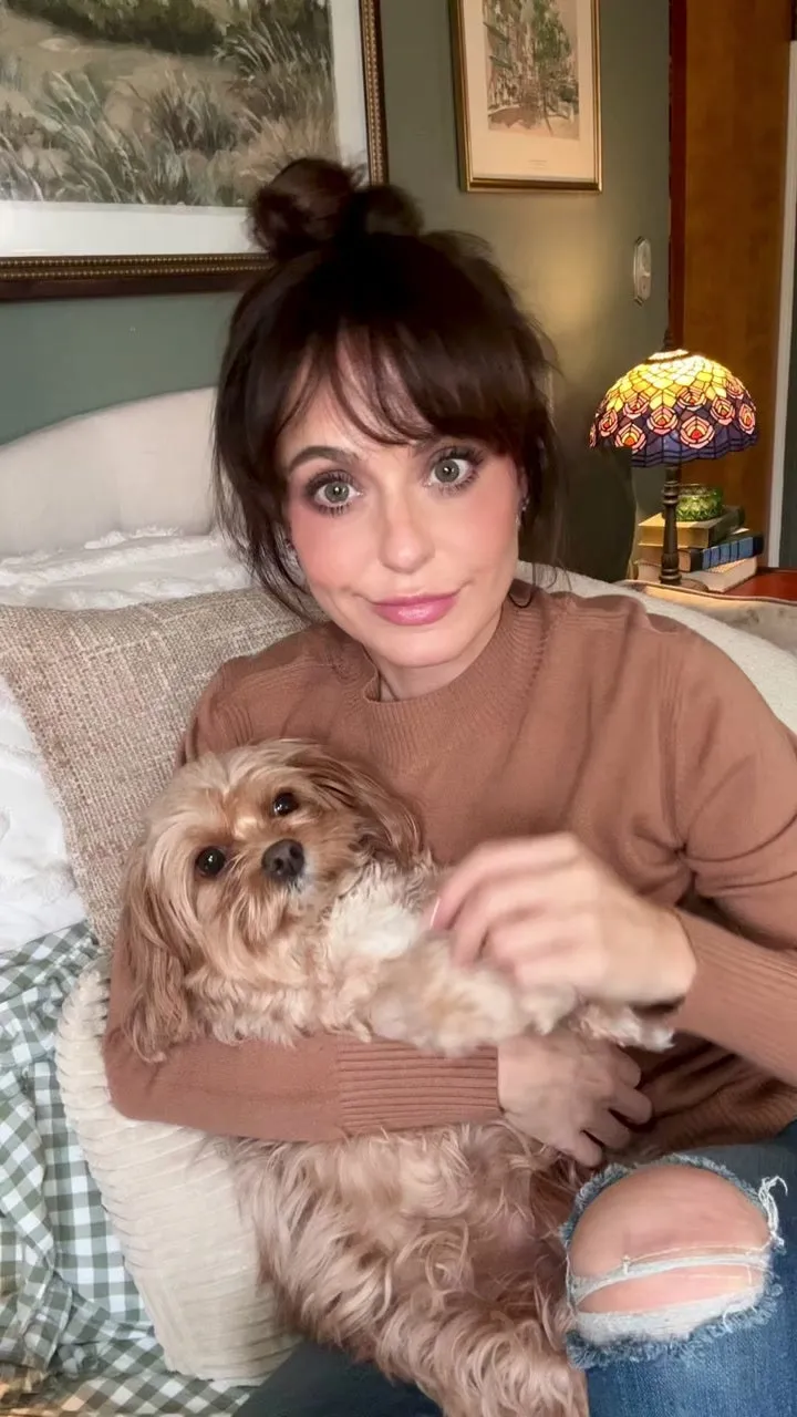 A customer sitting on a bed holding her small fluffy terrier mix
