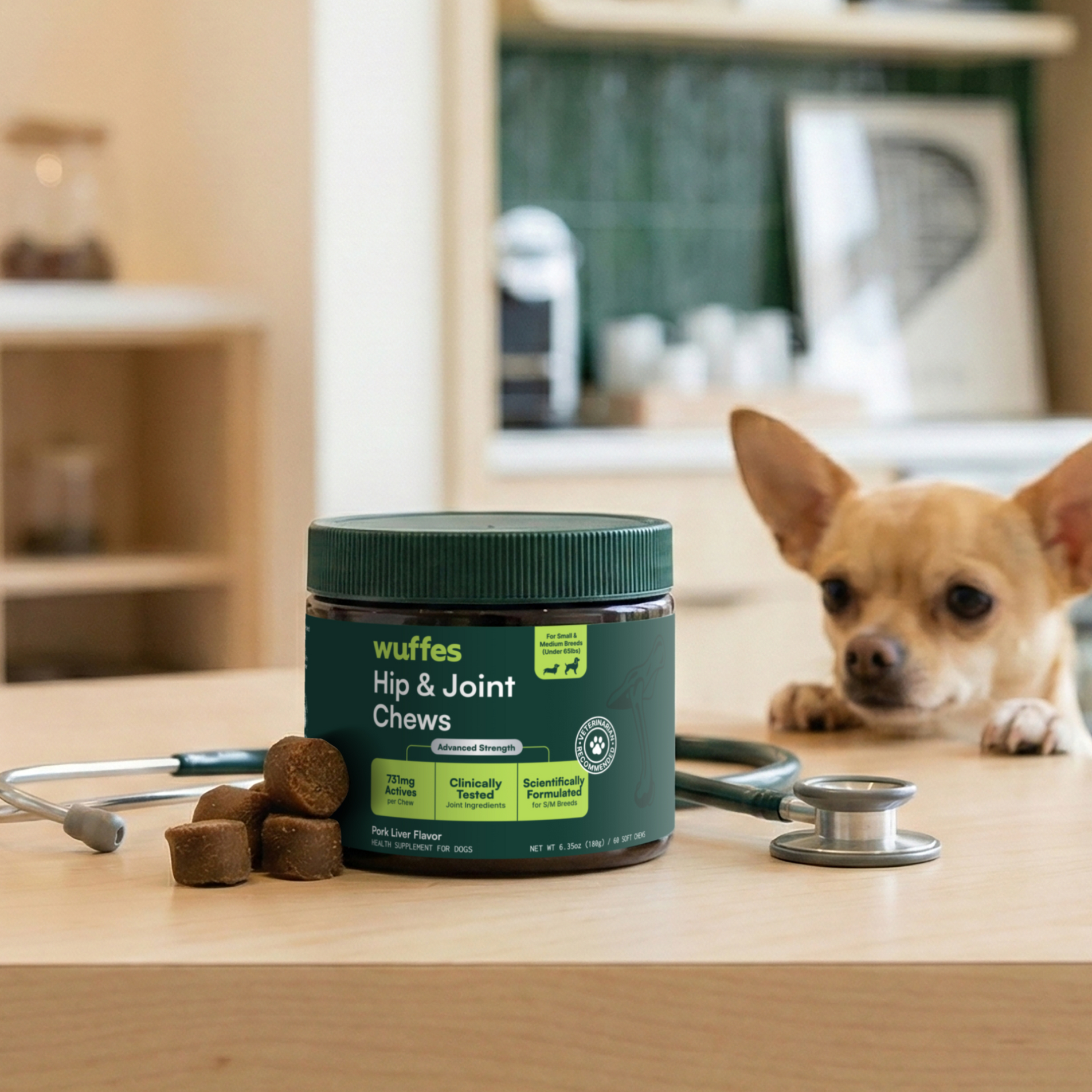 Container of Wuffes Hip and Joint Chews with chews and a small dog resting head on table nearby
